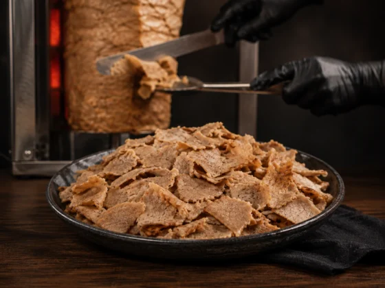 Gesneden döner kebab met dönerrol op de achtergrond