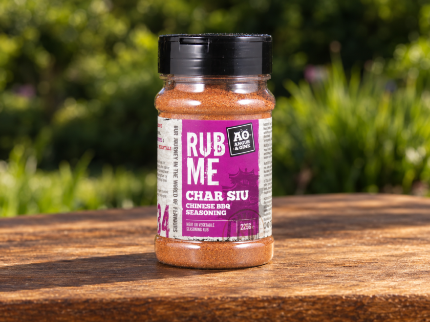 Pot Angus & Oink Char Siu Rub rub op een houten tafel met onscherp groen op de achtergrond