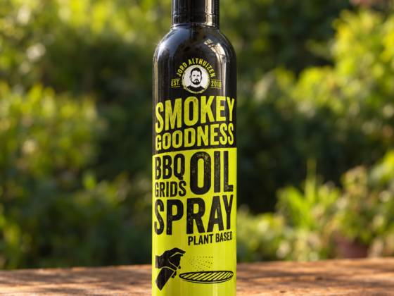 Fles Smokey Goodness BBQ Grids Oil Spray op een houten tafel in een groene buitenomgeving