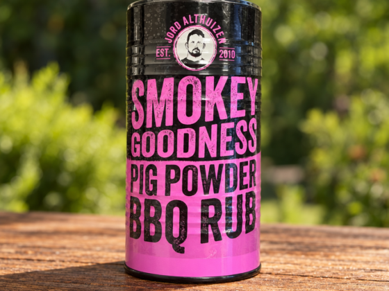 Zwart-roze verpakking Smokey Goodness Pig Powder Rub op een houten tafel buiten