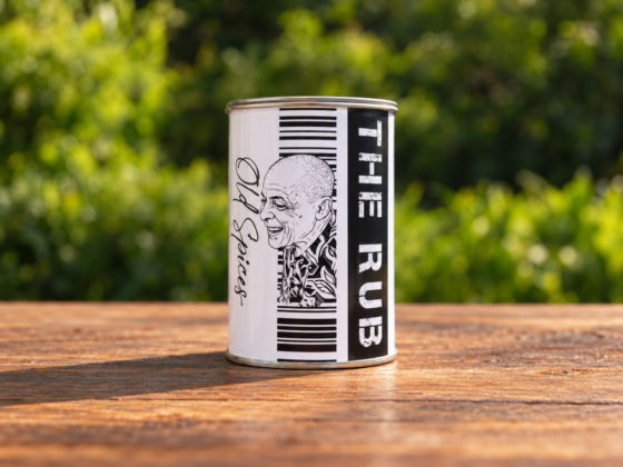 Blik The Old Spices met zwart-wit etiket op een houten tafel tegen een groene achtergrond