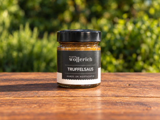 Pot Truffelsaus Wollerich met zwarte deksel op een houten tafel, gefotografeerd tegen een groene achtergrond